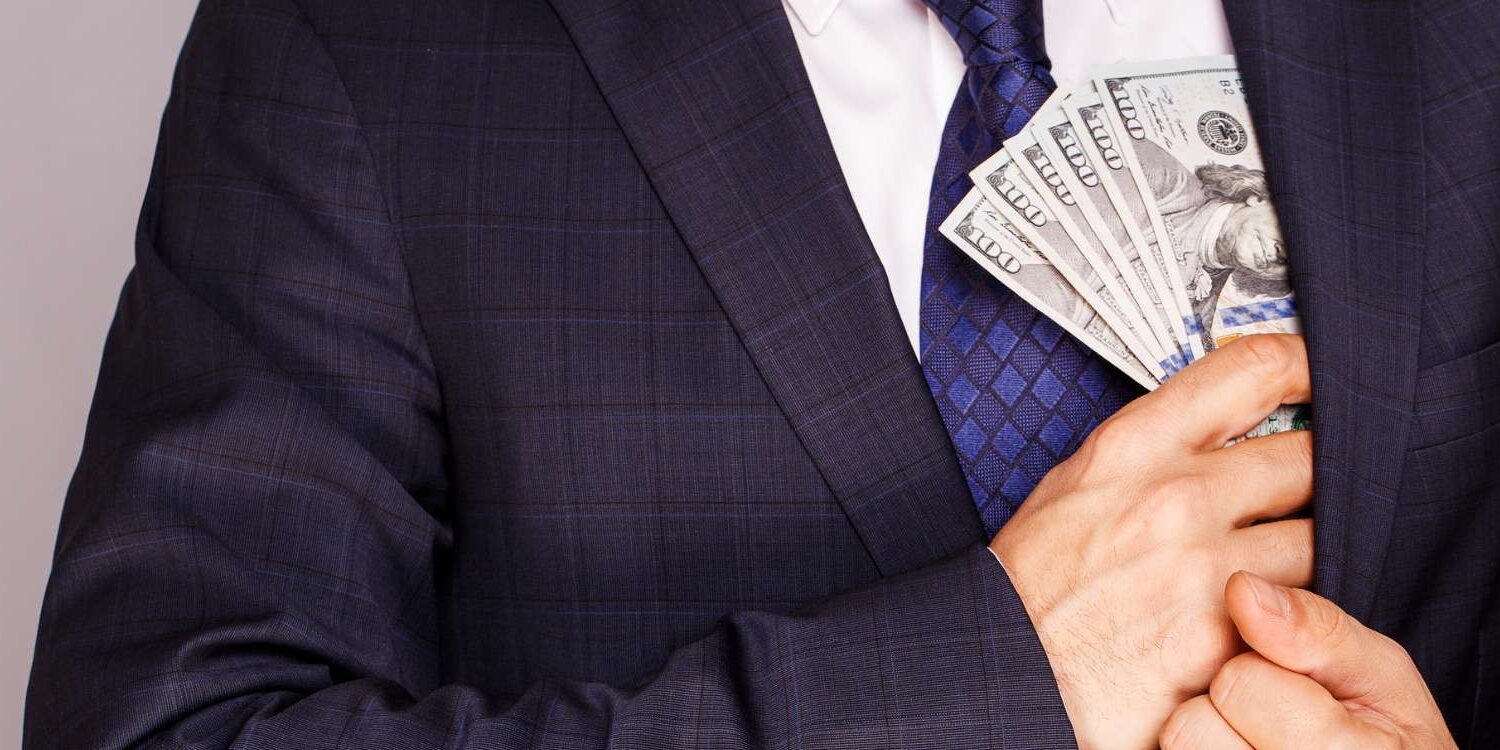 businessman putting money in suit jacket pocket picture id874316744 1500x750