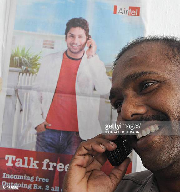 A Sri Lankan man talks on his cellular phone in front of a poster showing Sri Lankan cricketer Kumar Sangakkara promoting Indian cellular operator Bharti Airtel in Colombo on January 13, 2009. Operating under the brand name Airtel, Bharti has become the fifth mobile operator in Sri Lanka's tightly contested market, promising to offer cheaper calls to lure new customers. AFP PHOTO/Ishara S. Kodikara (Photo credit should read Ishara S. KODIKARA/AFP via Getty Images)