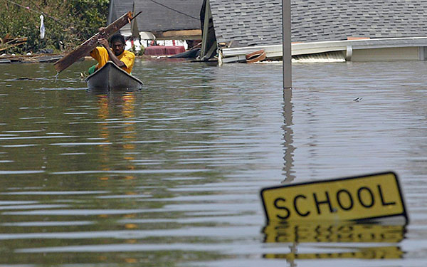 A resident uses a board to paddle through flood waters in New Orleans 30 August 2005 following Hurricane Katrina.  Hurricane-battered New Orleans was consumed by a catastrophe of unimagined scale Tuesday, cut off from the outside world, submerged by rising floodwaters and troubled by signs of fraying public order.   AFP PHOTO / James NIELSEN (Photo credit should read JAMES NIELSEN/AFP/Getty Images)