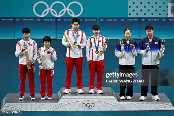 (From L) Silver medalists North Korea's Ri Jong Sik, and North Korea's Kim Kum Yong, gold medalists China's Wang Chuqin and China's Sun Yingsha, bronze medalists South Korea's Shin Yubin and South Korea's Lim Jonghoon celebrate on the podium at the end of their mixed table tennis doubles competition at the Paris 2024 Olympic Games at the South Paris Arena in Paris on July 30, 2024. (Photo by WANG Zhao / AFP) (Photo by WANG ZHAO/AFP via Getty Images)