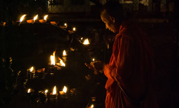 Kataragama, Sri Lanka  July 25, 2009: Buddhist nun lighting traditional oil lamps