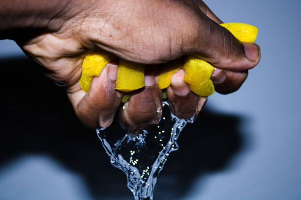 Squeezing a wet sponge in a bright background.