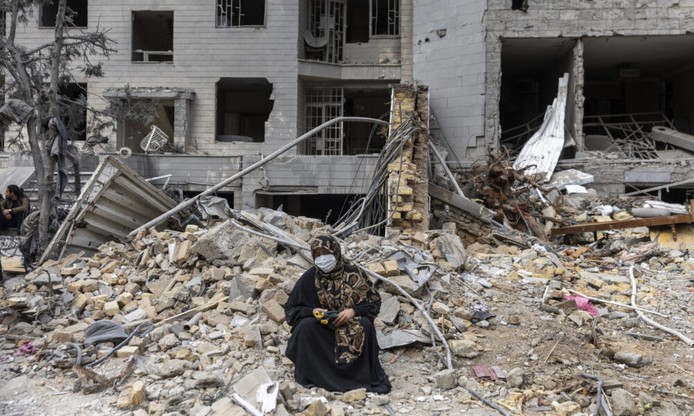 iranian woman in rubble scaled e1773946532603 1000x600