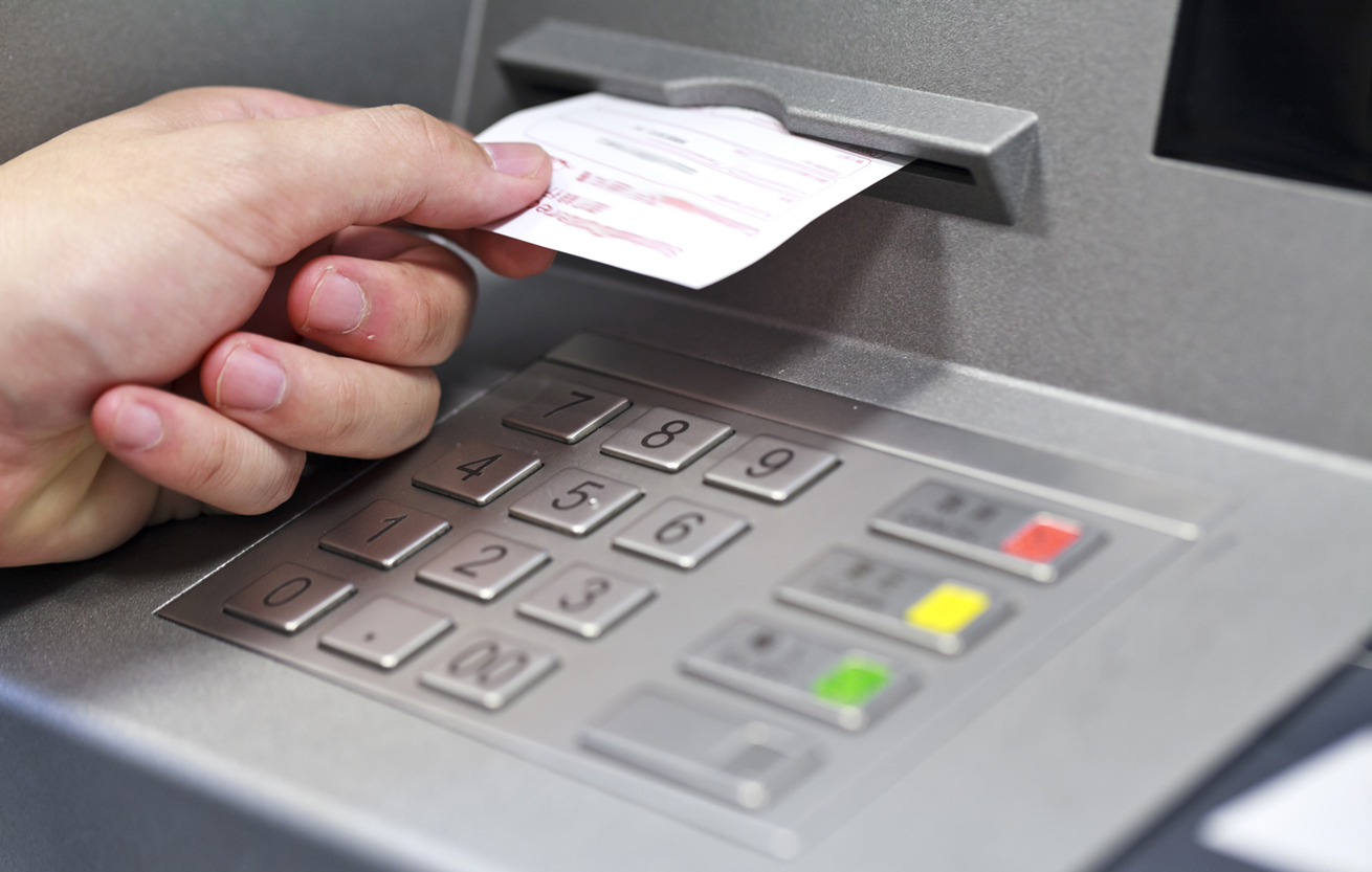 A hand taking a receipt of an Automated Teller Machine