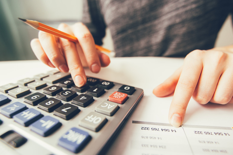 Closeup of accountant counting on calculator and working with table