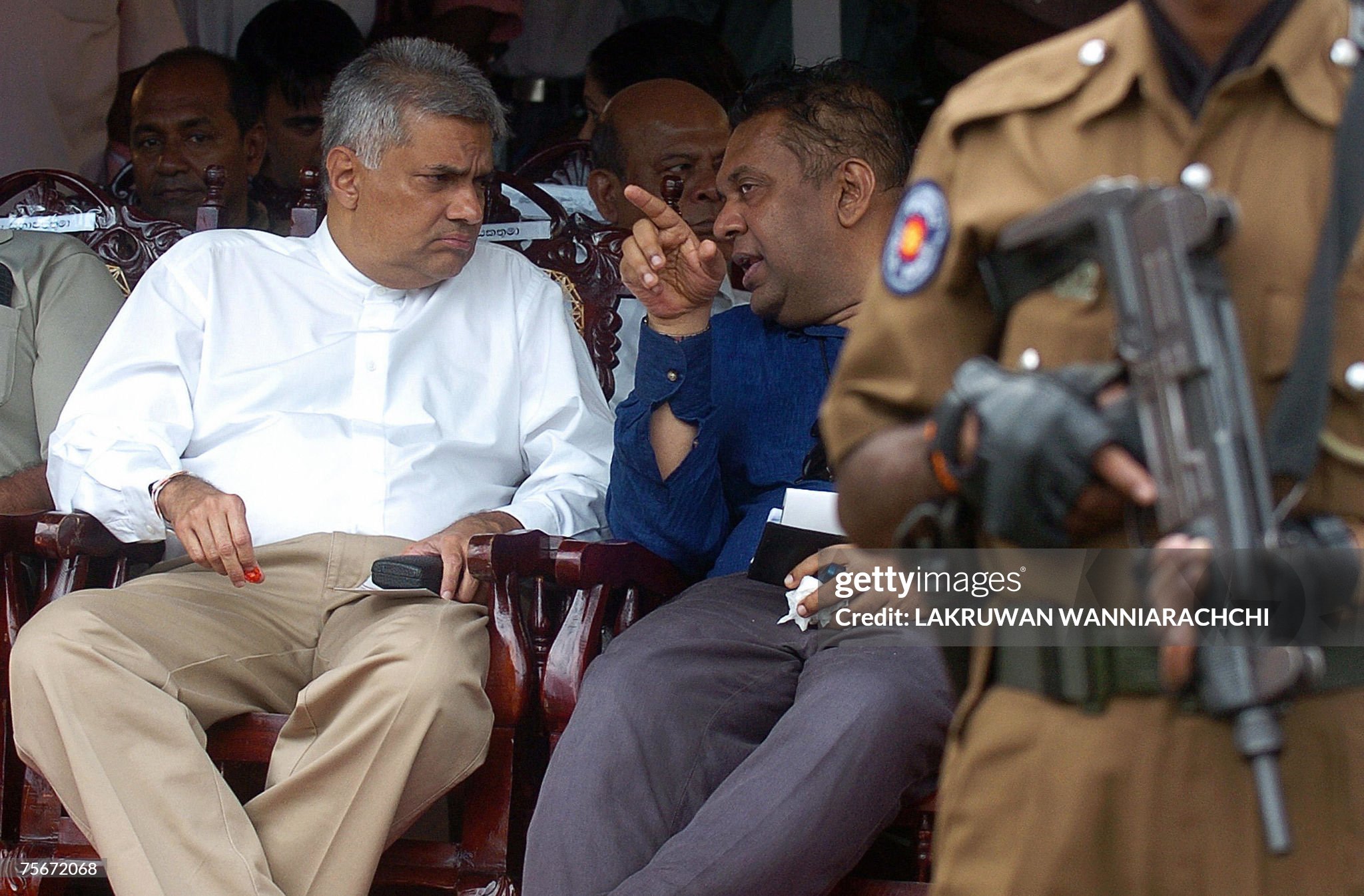 Colombo, SRI LANKA: Sri Lanka's leader of the main opposition Ranil Wickremasinghe (L) listens to former foreign minister Mangala Samaraweera (R) as a policeman stands guard at a mass rally in Colombo, 26 July 2007.  Thousands of opposition activists and ruling party dissidents took to the streets in Colombo to protest against human rights violations and high living costs. AFP PHOTO/Lakruwan WANNIARACHCHI (Photo credit should read LAKRUWAN WANNIARACHCHI/AFP via Getty Images)