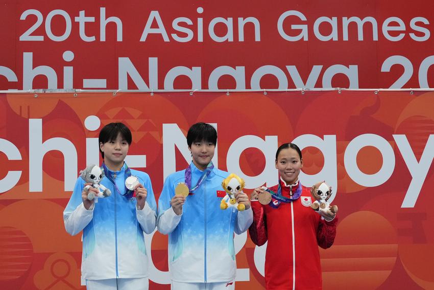 Gold medalist Yu Zidi of China, center, flanked by silver medalist Chang Mohan of China, left, and bronze medalist Misa Okuzono of Japan pose on the podium after the women's 200-meter butterfly final in swimming at the Asian Games in Tokyo, Japan, Sunday, Sept. 20, 2026. (AP Photo/Hiro Komae)