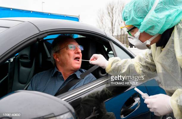 Peter Keck (L), spokesman of the Esslingen district administration, poses from a car for photographers to demonstrate how works the new "Drive-In" for tests of the novel coronavirus SARS-CoV-2 which can cause COVID-19, in Nuertingen, southern Germany, on March 9, 2020 during a presentation of the drive-in for the media. - The number of coronavirus cases in Germany has passed 1,000, official data from the Robert Koch Institute disease control centre showed. (Photo by THOMAS KIENZLE / AFP) (Photo by THOMAS KIENZLE/AFP via Getty Images)