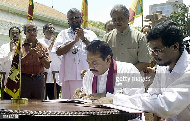 COLOMBO, SRI LANKA:  Sri Lankan Prime Minister Mahinda Rajapakse (C) and Secretary of the Marxist JVP,(People's Liberation Front) Tilvin Silva (R) are applauded by officials as they sign an agreement in Colombo, 08 September 2005.   Rajapakse signed a deal with the island's main Marxist party under which he agreed to drop plans to share power with Tiger rebels, but said he hoped the move will not lead to a resumption of war.  AFP PHOTO/Lakruwan WANNIARACHCHI  (Photo credit should read LAKRUWAN WANNIARACHCHI/AFP via Getty Images)