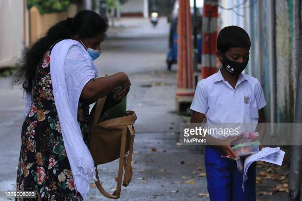A Sri Lankan student  wearing a protective mask heads towards the exam center as his mother (L) checks his bag after handing over the admission papers and food near an examination center for Grade-5 scholarship exam at Colombo, Sri Lanka on 11 October 2020. (Photo by Tharaka Basnayaka/NurPhoto via Getty Images)
